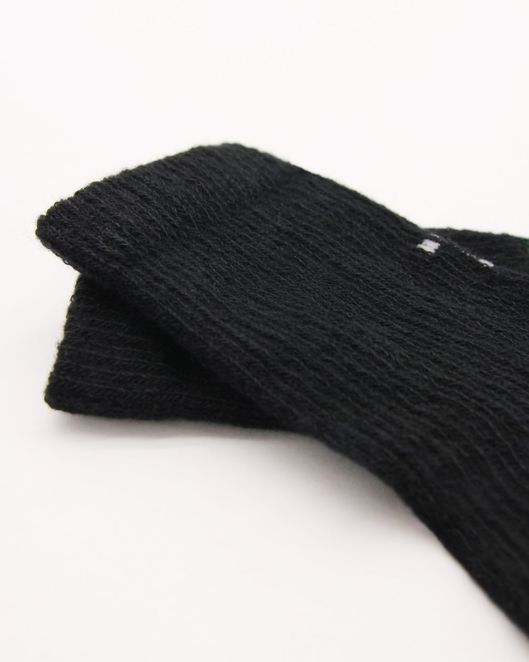 Knitting detail of black and evergreen baby socks